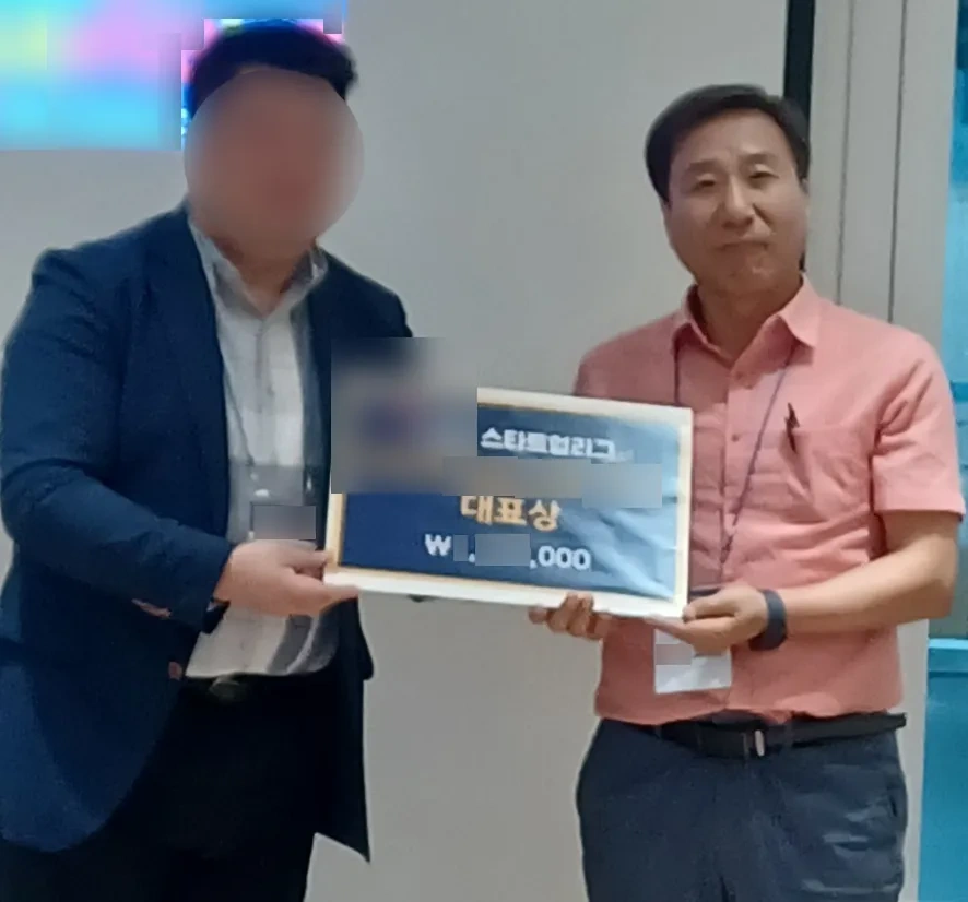 도전! 2023 은평스타트업리그 시상식 현장. 브이로프 황의범 대표가 '국민대학교기술지주 대표상' 판넬을 시상자와 함께 들고 있다. 시상자의 얼굴과 명찰, 판넬에 적힌 상금액은 흐리게 처리했다.