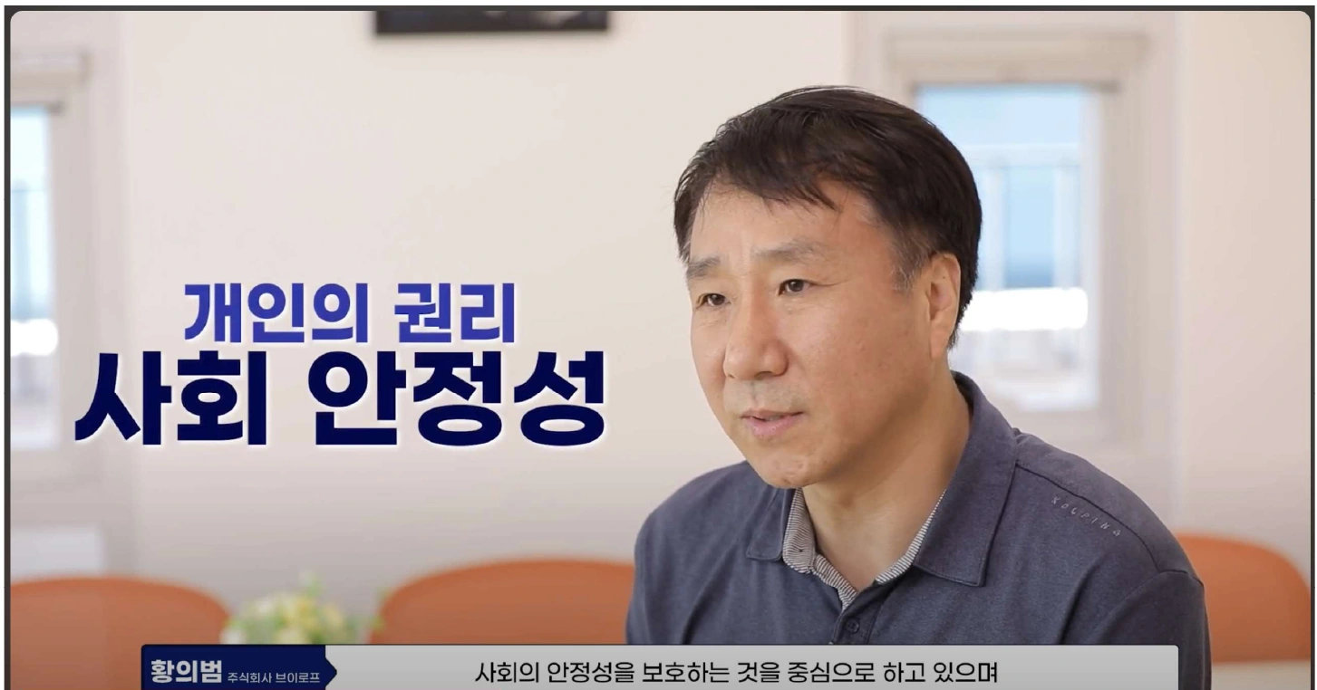 회사 소개 영상의 한 장면. 대표 황의범이 인터뷰하는 화면에 '개인의 권리 / 사회 안정성'이라는 자막이 있다.